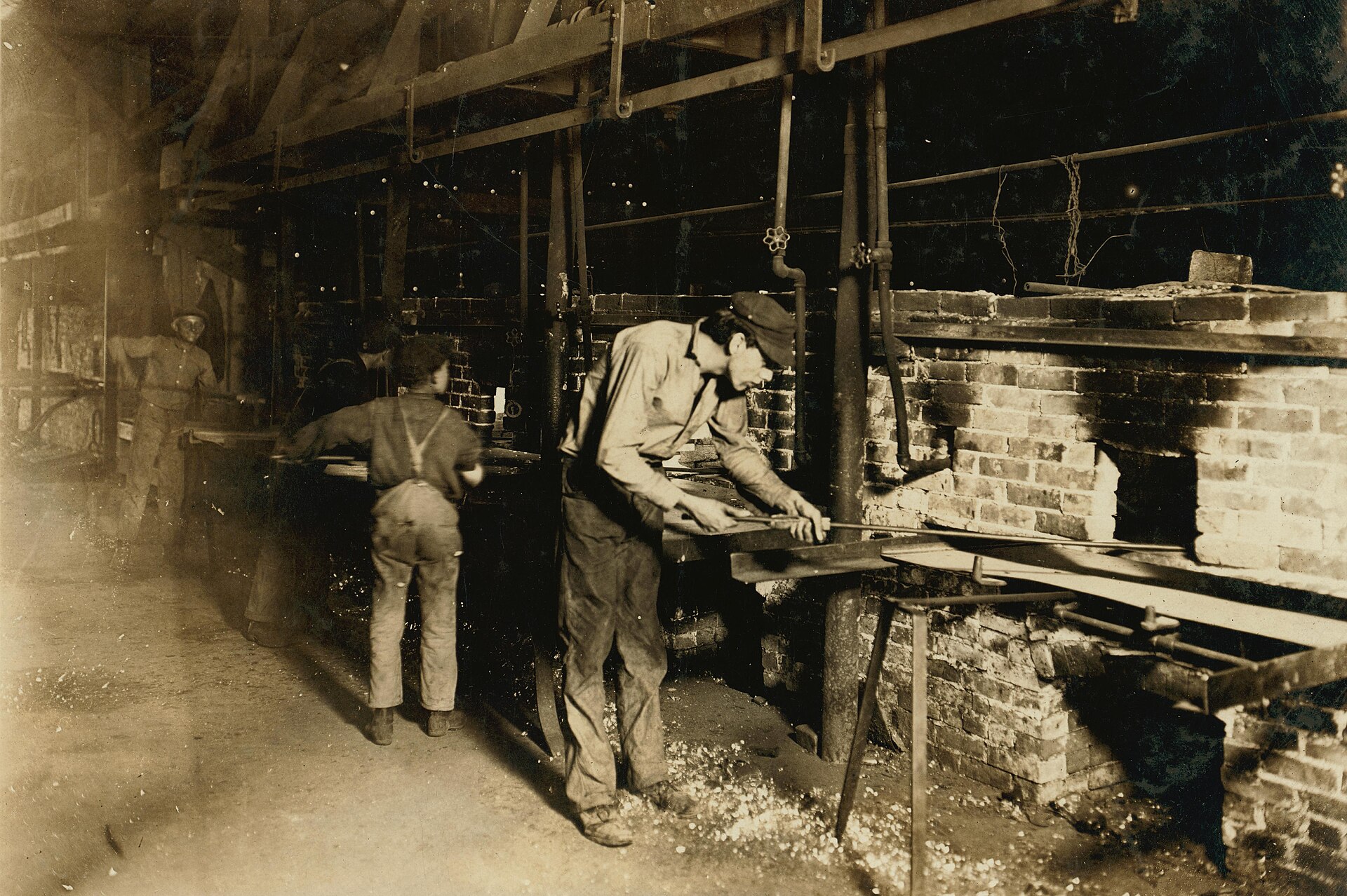 Historic glassworkers putting bottles into an annealing oven