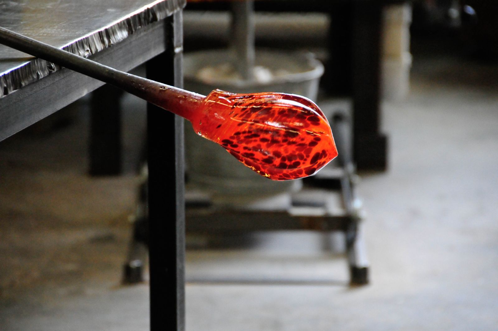 A glowing orange gather of molten glass on the end of a blowpipe