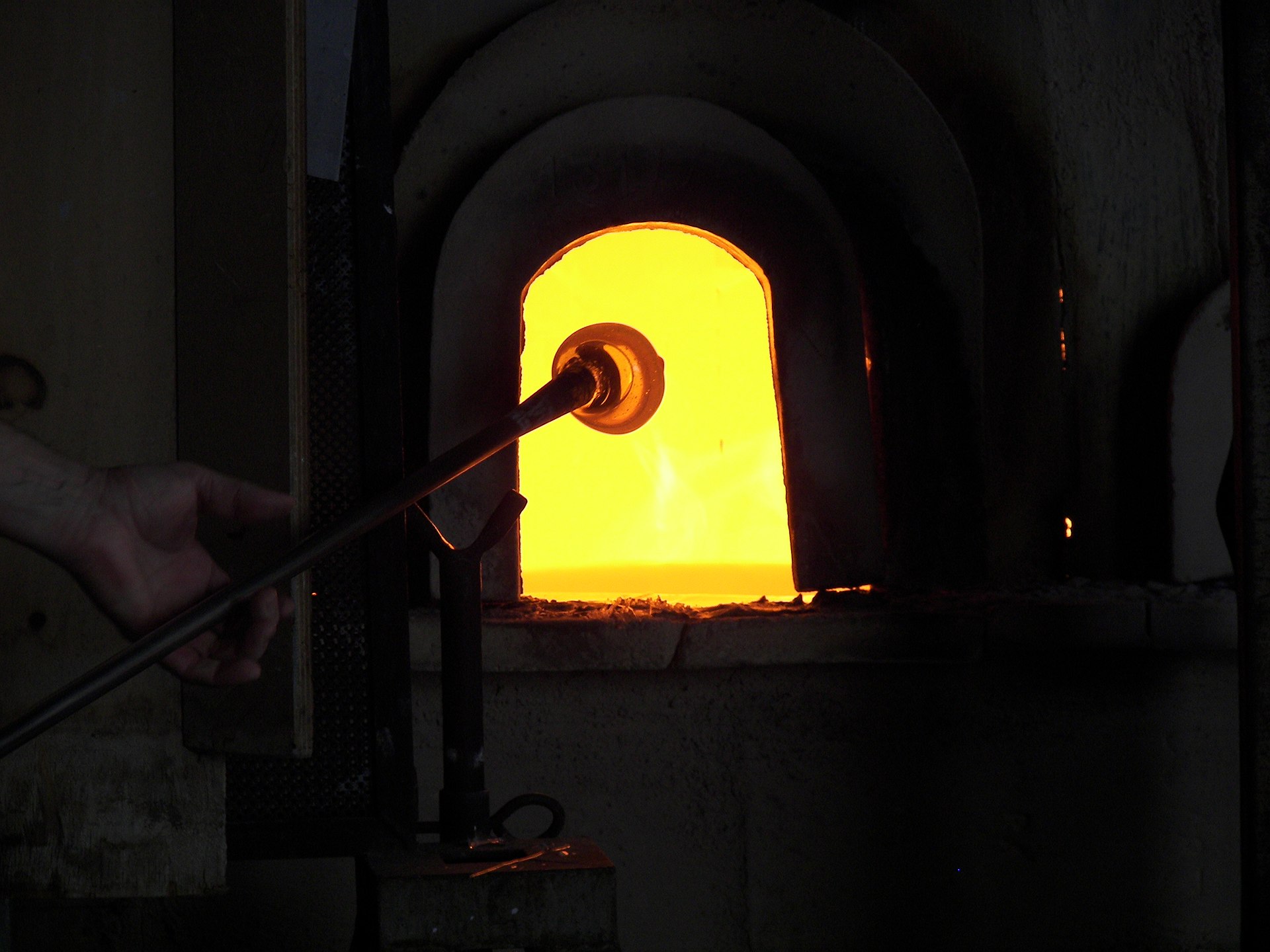 A blowpipe entering the bright opening of a glass furnace